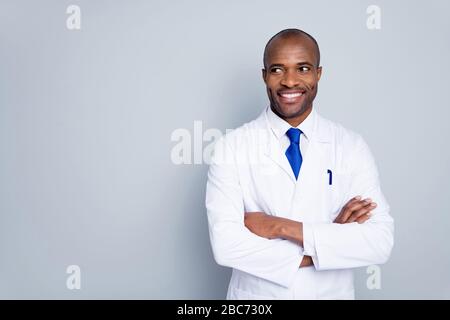 Photo of cheerful dark skin doc guy virologist agent corona virus arms crossed pandemic expert look empty space interested wear white lab coat tie Stock Photo