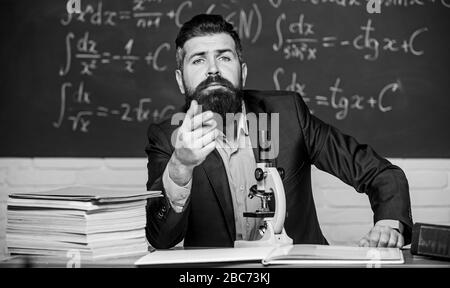 Educational conversation. Talking to students or pupils. School teacher concept. Teacher bearded man tell interesting story. Teacher charismatic hipster sit at table classroom chalkboard background. Stock Photo