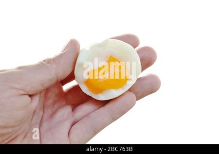 boiled egg half cut with creamy yolk holding on hand in white background Stock Photo