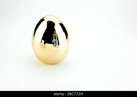 Single Shiny golden egg with reflection of invitation, candles and Stock Photo