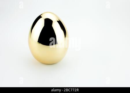 Single Shiny golden egg with reflection isolated on white Stock Photo