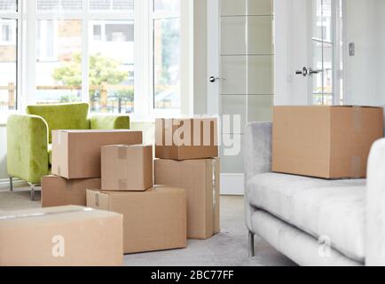 Cardboard carton boxes stack with household belongings in modern house living room. Packed containers on floor in new home. Stock Photo