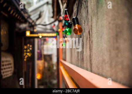 Colorful light bulbs decoration hanging on a wall in an alley. Stock Photo