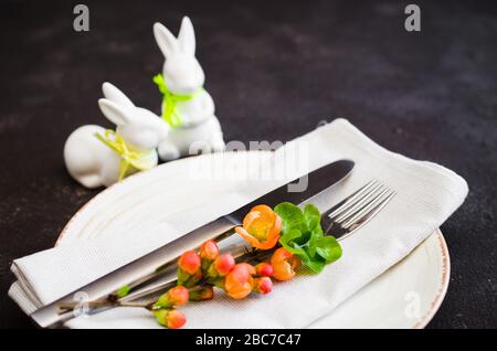 Easter table setting with spring flowering branches, cutlery and decorative rabbits. Spring Easter background for menu. Holidays background with copy Stock Photo
