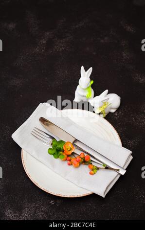 Easter table setting with spring flowering branches, cutlery and decorative rabbits. Spring Easter background for menu. Holidays background with copy Stock Photo
