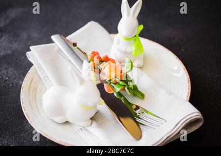 Easter table setting with spring flowering branches, cutlery and decorative rabbits. Spring Easter background for menu. Holidays background with copy Stock Photo