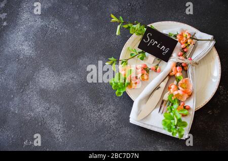 Festive table place setting with spring blossoming branch on a dark concrete background. Copy space Stock Photo