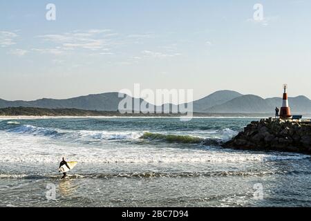 Surfer and Barra da Lagoa Lighthouse. Florianopolis, Santa Catarina, Brazil. Stock Photo