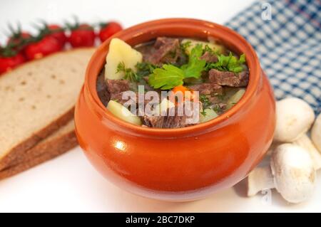 Roast in a pot with beef meat and potatoes on the table