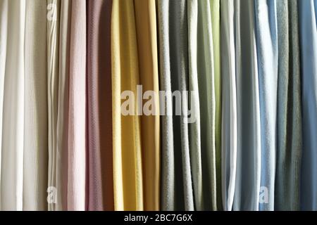 Mix colorful and pattern hanging vertical stripe textile, fabrics, cloths on the rack. Mix of pastel color of textile. Stock Photo