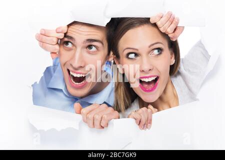 Couple peeping through hole on paper Stock Photo