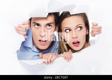 Couple peeping through hole on paper Stock Photo