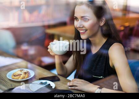 Young woman seen through cafe window Stock Photo