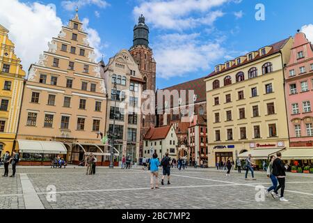 People in Wroclaw's main square, the rynek, with landmarks St Elizabeth's Church and the Hansel & Gretal houses behind. Wroclaw, Poland. July 2017. Stock Photo