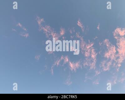 Wispy Pink Clouds Against A Blue Sky Stock Photo