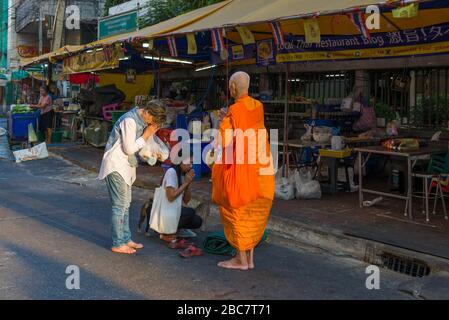 BANGKOK, THAILAND - DECEMBER 31, 2018: Two women receive morning blessing from an elderly Buddhist monk Stock Photo