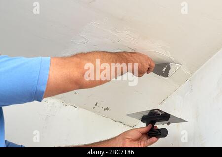 Man putting spackle on a ceiling during renovating works Stock Photo