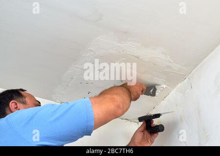 Man putting spackle on a ceiling during renovation Stock Photo