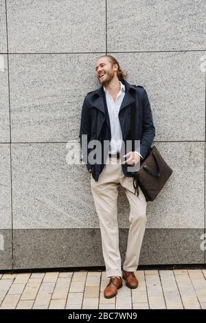 Handsome happy young bearded businessman standing outdoors in the street Stock Photo