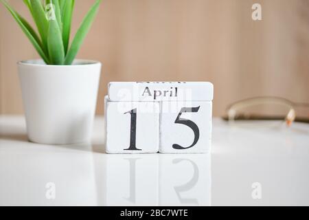 Date on white wooden cubes - the fifteenth, 15 April on a white table. Close up. Stock Photo
