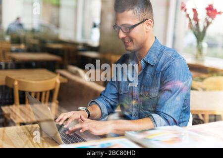 Young man using laptop at cafe Stock Photo