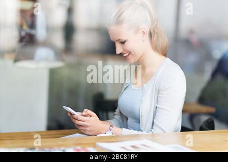 Woman using mobile phone at cafe Stock Photo