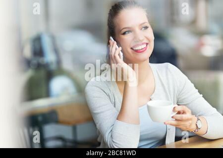 Woman using mobile phone at cafe Stock Photo