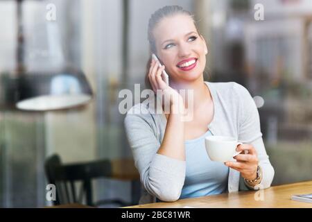Woman using mobile phone at cafe Stock Photo