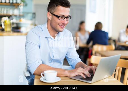 Young man using laptop at cafe Stock Photo