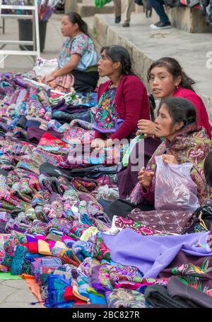 Maya women selling shawls sitting on street pavement at Calle General Utrilla in San Cristobal de las Casas, Chiapas, Mexico Stock Photo