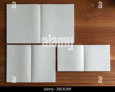 Open the blank notebooks in 3 different sizes on the wooden desk. Empty space for your text. Directly above. Stock Photo