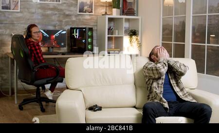 Upset man throwing wireless controller on the couch after losing after playing video games. Girlfriend in the background. Stock Photo