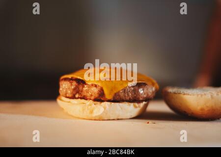 Cheeseburger without top part of the bun lying on the table Stock Photo