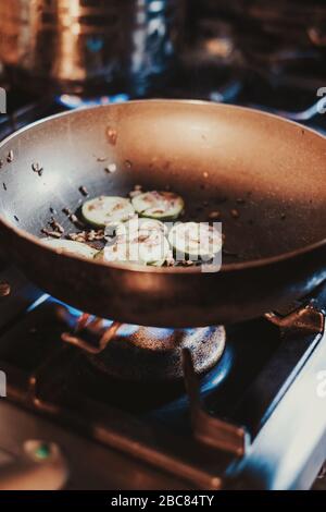 Onions cooking in oil in the frying pan on the gas stove Stock Photo