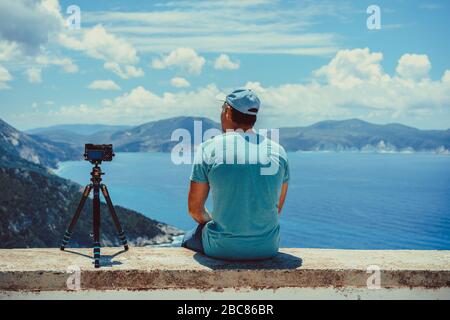 Summer holiday vocation visiting Greece. Male photographer enjoying capture time lapse moving cloudscape coastline and Mediterranean sea with camera o Stock Photo
