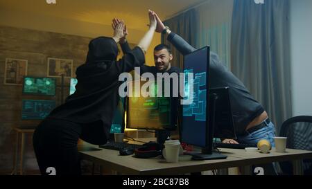 Team of cyber criminals celebrate after a successful hack on government server. Hacker girl. Stock Photo