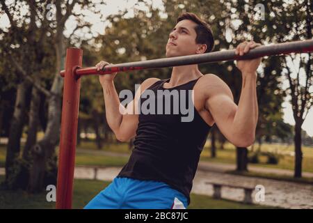 Man doing chin ups on the bar in the park gym Stock Photo