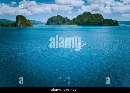 Aerial view of island hopping boats on open waved sea on the way to tour B in picturesque archipelago. El Nido, Palawan, Philippines.