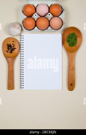 Wooden ladles with spices, eggs and garlic with a blank notebook page Stock Photo