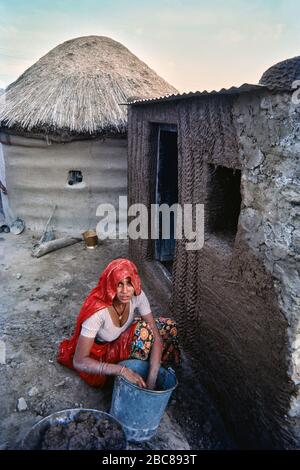 04 Mar 2020 woman applying Mud and cow dung plaster on house wall Sri Dungargarh Bikaner District Rajasthan India Stock Photo
