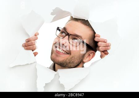 Man looking through hole in paper Stock Photo