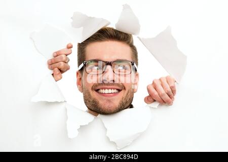 Man looking through hole in paper Stock Photo
