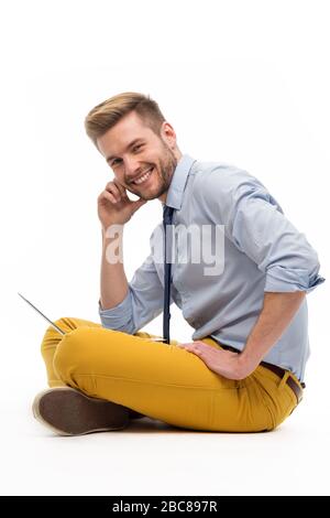 Portrait of young man sitting on the floor with laptop Stock Photo
