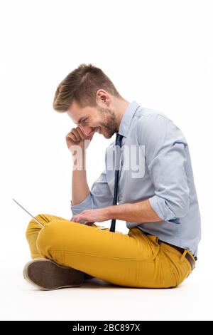 Portrait of young man sitting on the floor with laptop Stock Photo