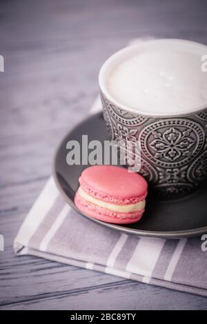 Gray cup of coffee latte and pink strawberry macaroon on a gray background Stock Photo