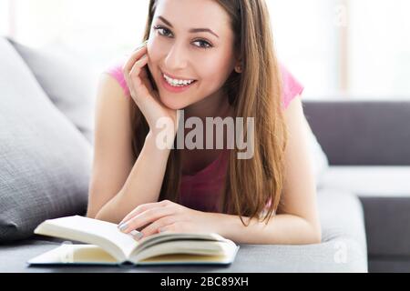 Woman reading book on sofa Stock Photo