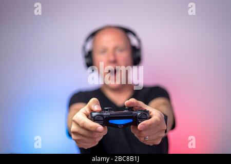 Gamer with headphones and gamepad having a lot of fun. Gamepad in Stock Photo