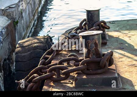 Iron rusty ropes are located on bitts close-up. Painted black Sunny day. Stock Photo