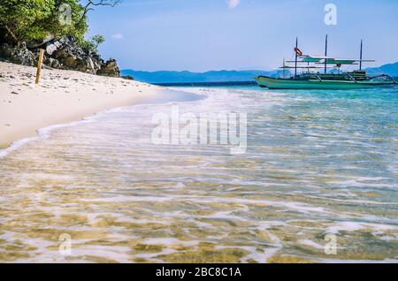 Traditional banca boat in clear water at sandy Beach near El Nido, Philippines. Stock Photo