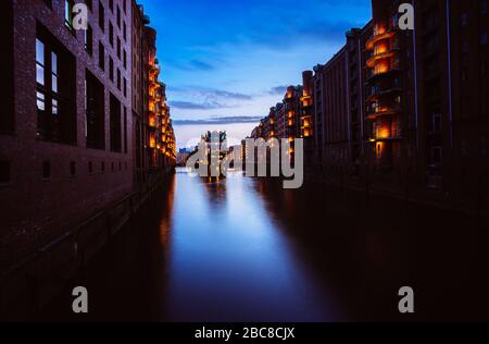 Blue hour in Warehouse District - Speicherstadt. Tourism landmark of Hamburg in twilight. View of Wandrahmsfleet in lantern light lamp. Place is locat Stock Photo